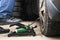 Man`s foot pumping up a flat car tyre or tire, which is deflated. Man Inflating car tyre with foot pump. Concept of checking a ca