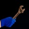 A man's hand in a blue glove holds a rusty wrench. Close-up