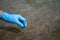 A man& x27;s hand in a blue glove takes a close-up of water into a test tube to measure the purity of water. Background