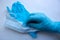 A man`s hand in a blue latex glove holds a mask on a white background. Protect your hands and face from viruses