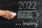 A man`s hand with a charging plug, a battery-shaped loading indicator showing loading and the text LOADING 2022