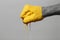 Man`s hand clenched into a fist smeared in yellow paint on a gray background, a creative idea concept of positive thinking and