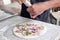 Man`s hand dressing an uncooked onions pizza on a marble table with copy space for your text