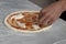 Man`s hand dressing an uncooked   pizza on a marble table with copy space for your text