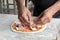 Man`s hand dressing an uncooked   pizza on a marble table with copy space for your text