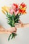 Man`s hand giving bouquet of flowers to woma`s hand on white background