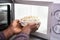 Man`s Hand Heating Food In Microwave Oven