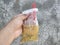 a man& x27;s hand is holding a drink in a plastic bag with a red pipette, the drink in Indonesian is called es cendol dawet