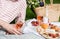 Man`s hand holding glass of rose wine, summer picnic with cheese and wine