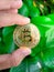 Man\'s hand holding a golden Bitcoin token coin.