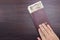 Man`s hand holding international passport and Japanese money on brown dark wooden table