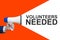 Man`s Hand Holding Megaphone With Speech Bubble VOLUNTEERS NEEDED. Announcement And Advertising