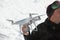A man`s hand holding a professional quadrocopter against the background of a snowy field