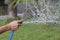 The man`s hand holds the blue rubber tube to inject water to Watering the tree.