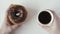 Man`s hand holds a donut and coffee soluble. Top view