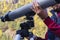 Man\\\'s hand holds large gray telescope, attaches stargazing equipment to tripod