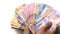 A man\\\'s hand holds a pile of rupiah banknotes