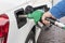 Man`s hand holds a refueling hose near the hatch of a gas tank of a car