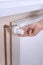 The man`s hand holds the temperature control valve on the radiator and sets the required value. White radiator and copper water pi