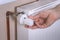 The man`s hand holds the temperature control valve on the radiator and sets the required value. White radiator and copper water pi
