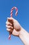 Man`s hand holds traditional Christmas striped candy cane