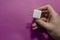 Man`s hand holds white DC wall adapter against pink background