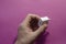 Man`s hand holds white DC wall adapter against pink background