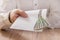 Man`s hand holds a white envelope filled with banknotes of the Polish currency and hands it over the table.