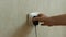 A man`s hand inserts a charger into a faulty electrical outlet. Home electrical repair concept. An electrical outlet sticking out