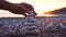 A man's hand makes a pyramid of stones on sunset. Concept of balance, harmony and meditation.