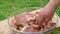 A man's hand marinates pieces of fresh pork in a dish.