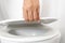 man`s hand opening the toilet lid
