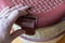 Man`s hand opens brown pet carrier basket. The closed plastic carrier stands on the floor of the living room. Close-up. Selective