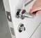 A man`s hand opens an interior door with a broken doorknob. Poor quality door hardware, breakage, damage