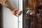 A man`s hand opens a white plastic door. Close up