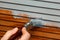 Man`s hand painting wooden panel door with a brush in lead grey colour