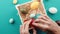 A man\'s hand is placing the colored Easter eggs in the basket