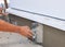 Man\'s hand plastering a wall insulation and house foundation with trowel.