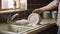 A Man\\\'s Hand Polishing a Clean Plate with a Towel in a Vintage Kitchen Setting. Generative AI