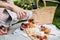 Man`s hand pouring rose wine into glasses, summer picnic