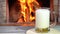 A man`s hand pours Beer into a glass, in front of a cozy fireplace, in country house.