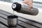 A man`s hand pours tea from a thermos into a Cup on a bench.