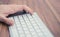 Man`s hand pressing escape button on wireless keyboard on wooden table