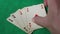 A man`s hand puts his four aces on the green table while playing poker.