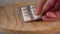 A man s hand puts a pack of medical white capsules on a wooden surface