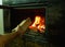 A man`s hand puts wood in the burning fireplace. Modern closed fireplace with glass