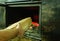 A man\\\'s hand puts wood in the burning fireplace. Modern closed fireplace with glass