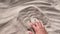 Man`s hand scatters sand through his fingers. Hand movement