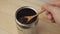 A man`s hand scoops coffee beans out of a jar with a wooden spoon. Slow motion