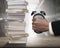 Man`s hand seizing alarm clock to deformation with stack books